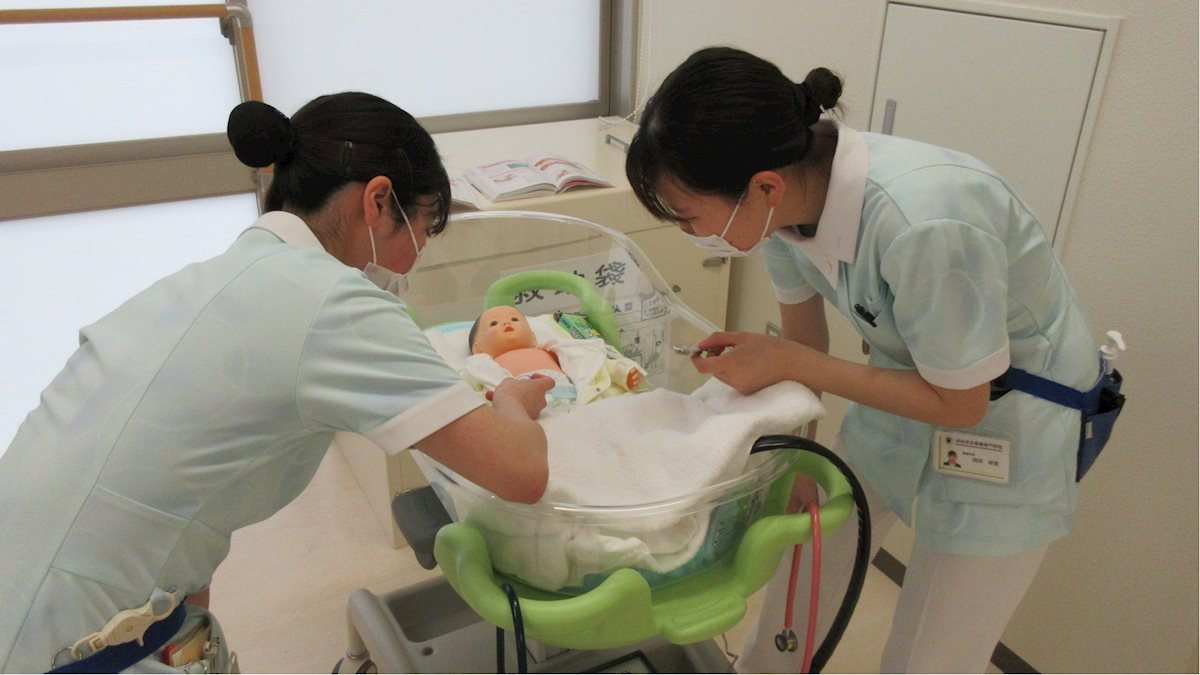 Two nursing students from the Hamamatsu Municipal Nursing College practice on an infant-sized manakin.